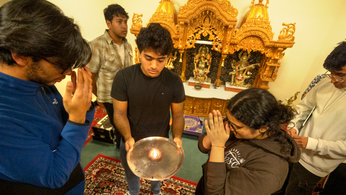 Sreang Hok/Cornell University Megh Prajapati ’26, (center) former Hindu Student Council president, and Esha Shah ’27 (right), HSC’s current president, take part in blessings in the Hindu Temple room in Anabel Taylor Hall. 