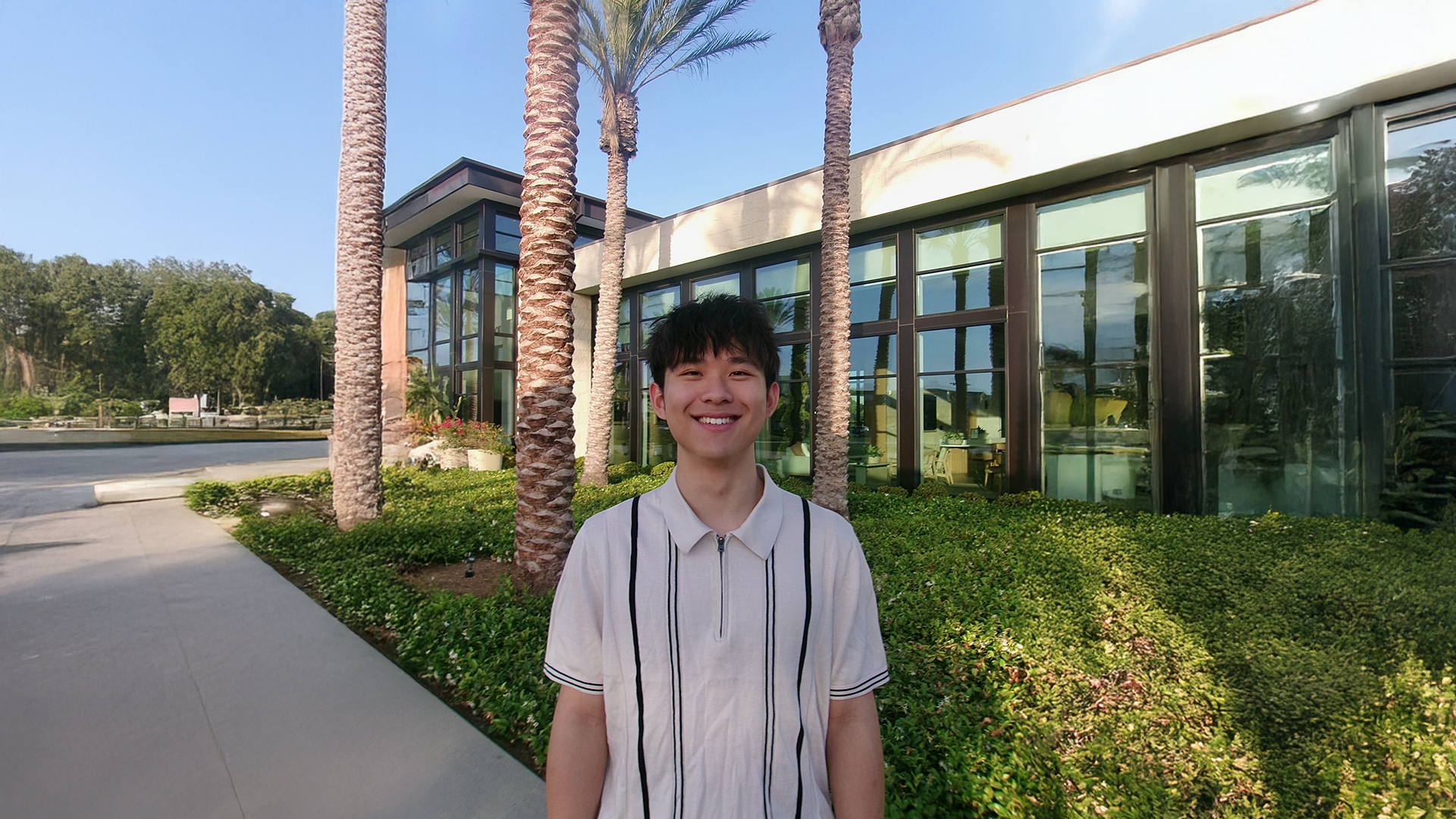 A color photo of a man smiling for a photo outside.