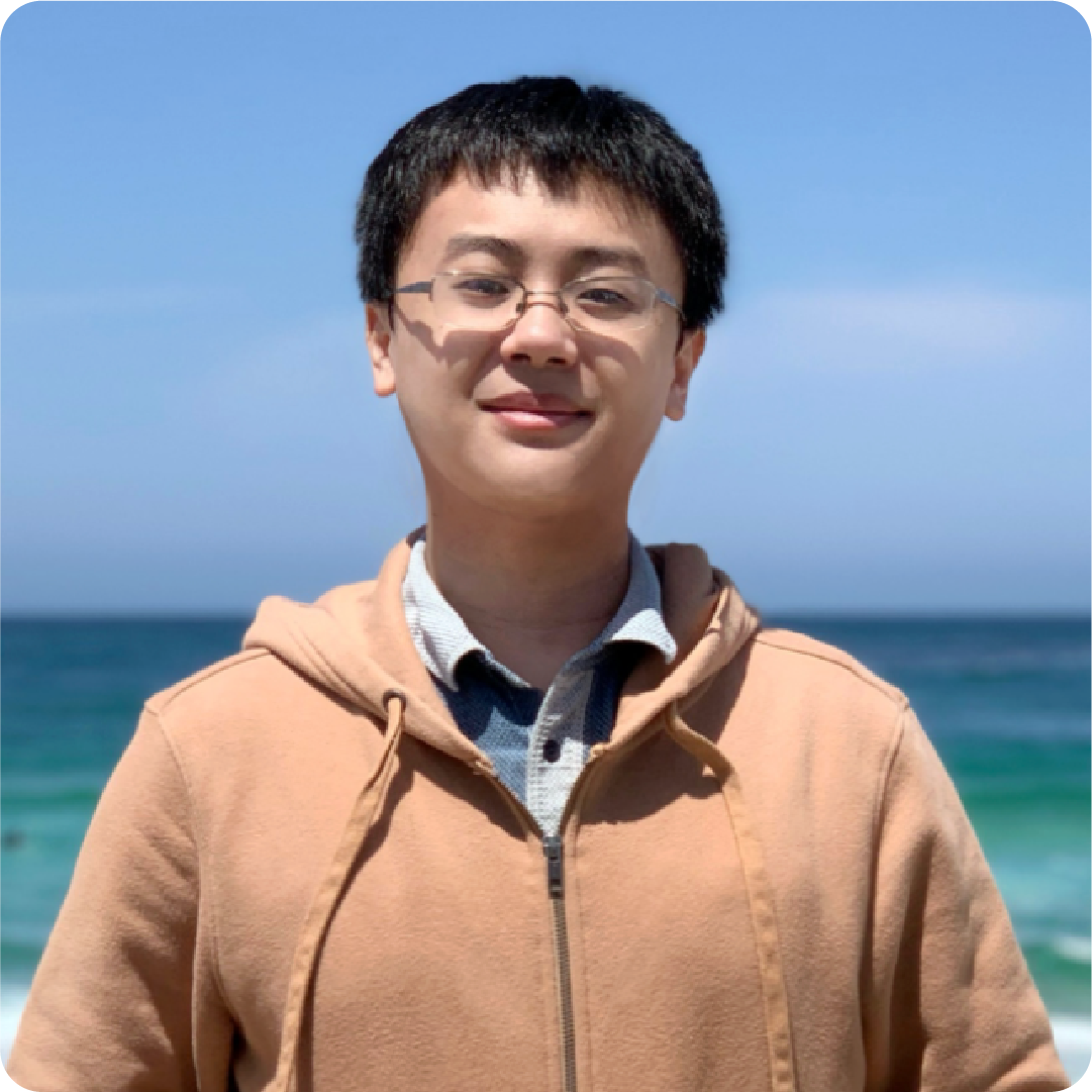 A color photo of a man standing by the ocean.
