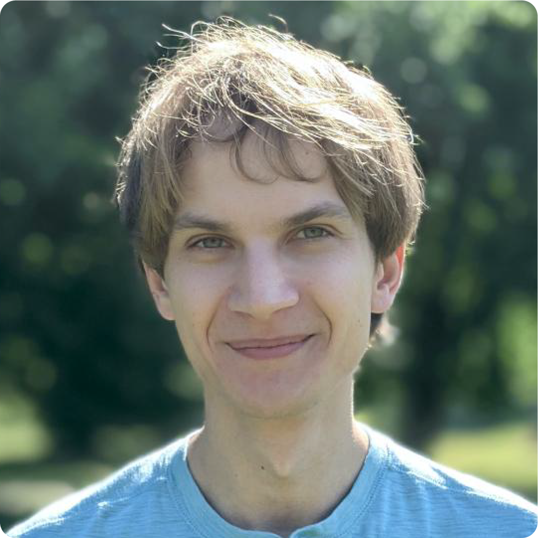 A color photo of a man smiling for a photo outdoors.