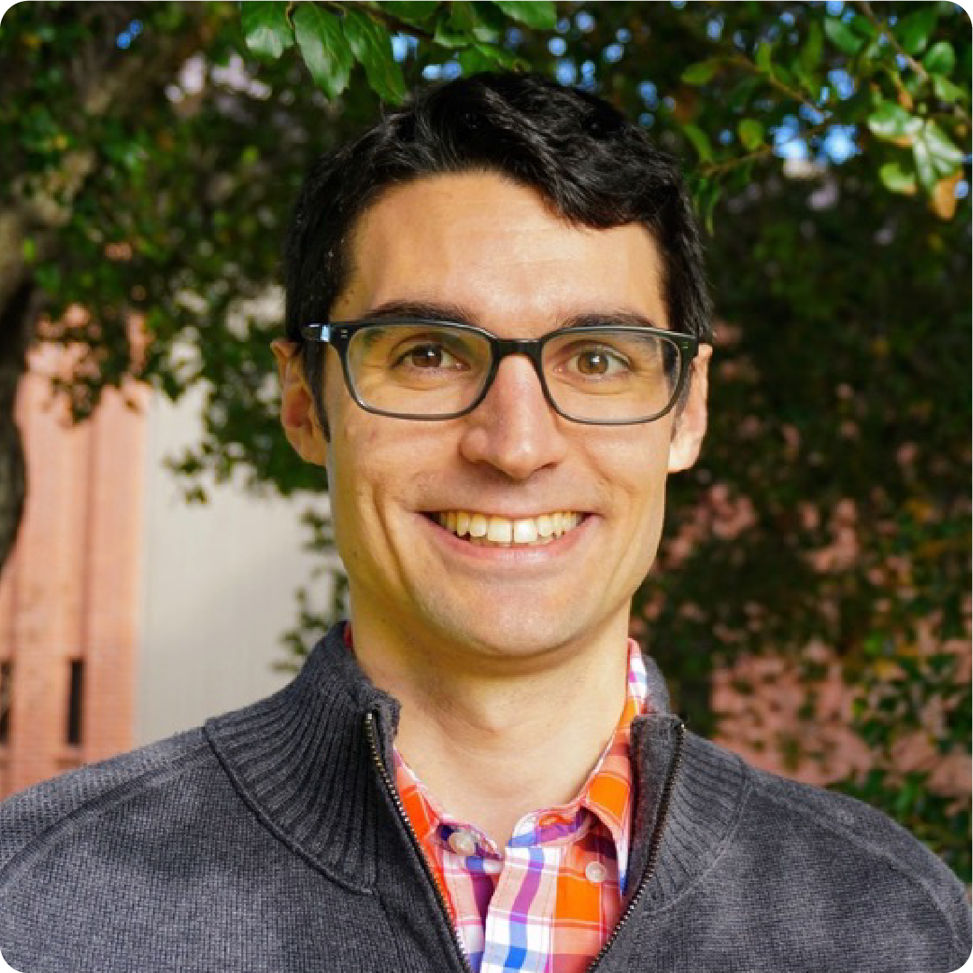 A color photo of a man with glasses, smiling for a photo.