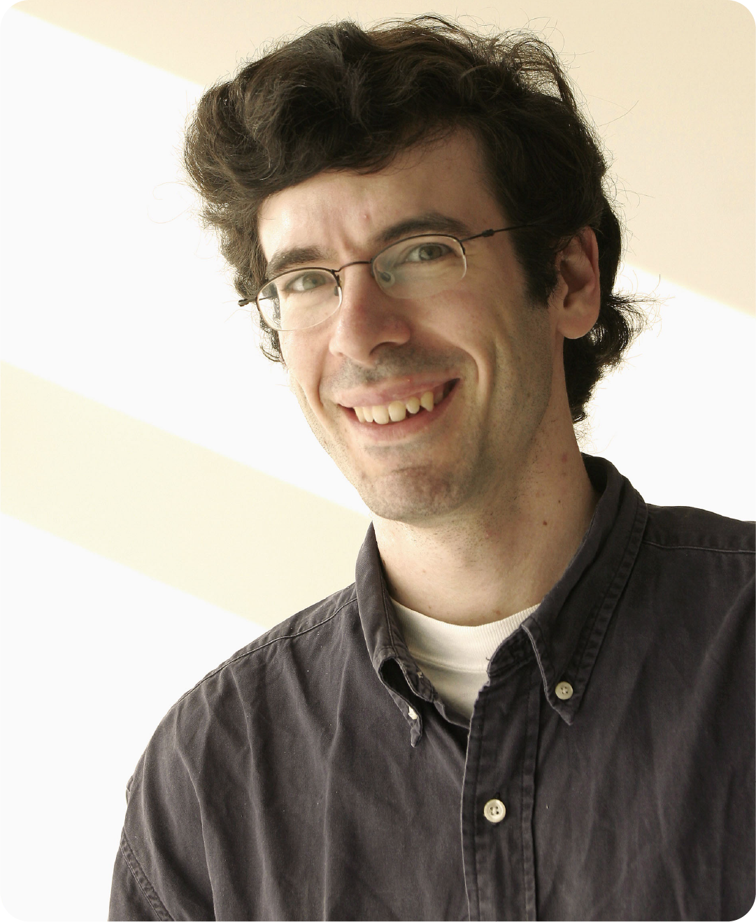 A color photo of a man with glasses.