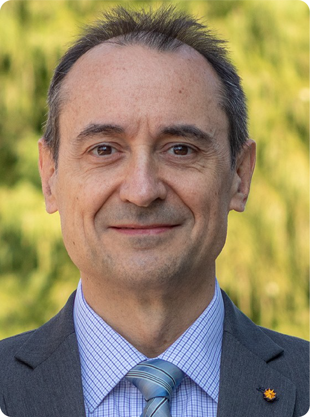 A color photo of a man wearing a suite and tie.