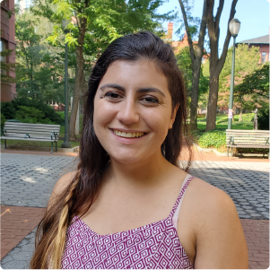 A color photo of a woman standing outside for a photo.