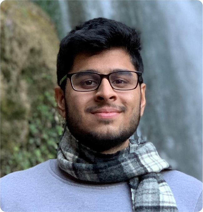 A color photo of a man with glasses wearing a scarf.
