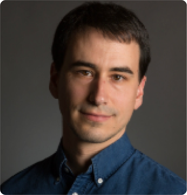 A color portrait of a man with a navy blue dress shirt.