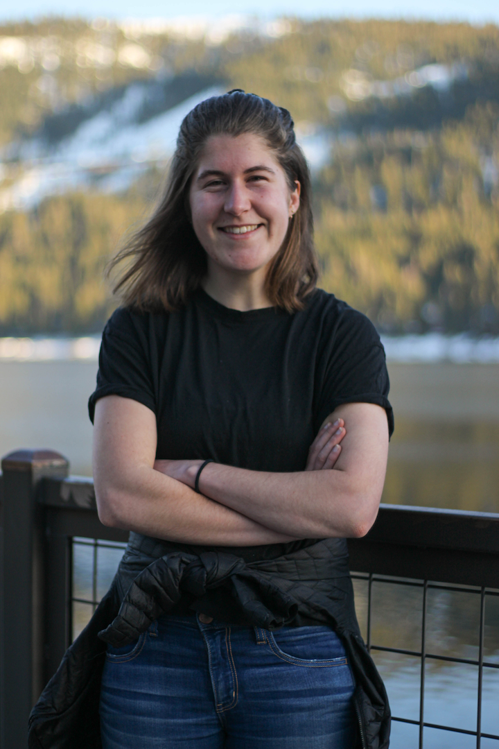 A color photo of a woman smiling for a photo outdoors.
