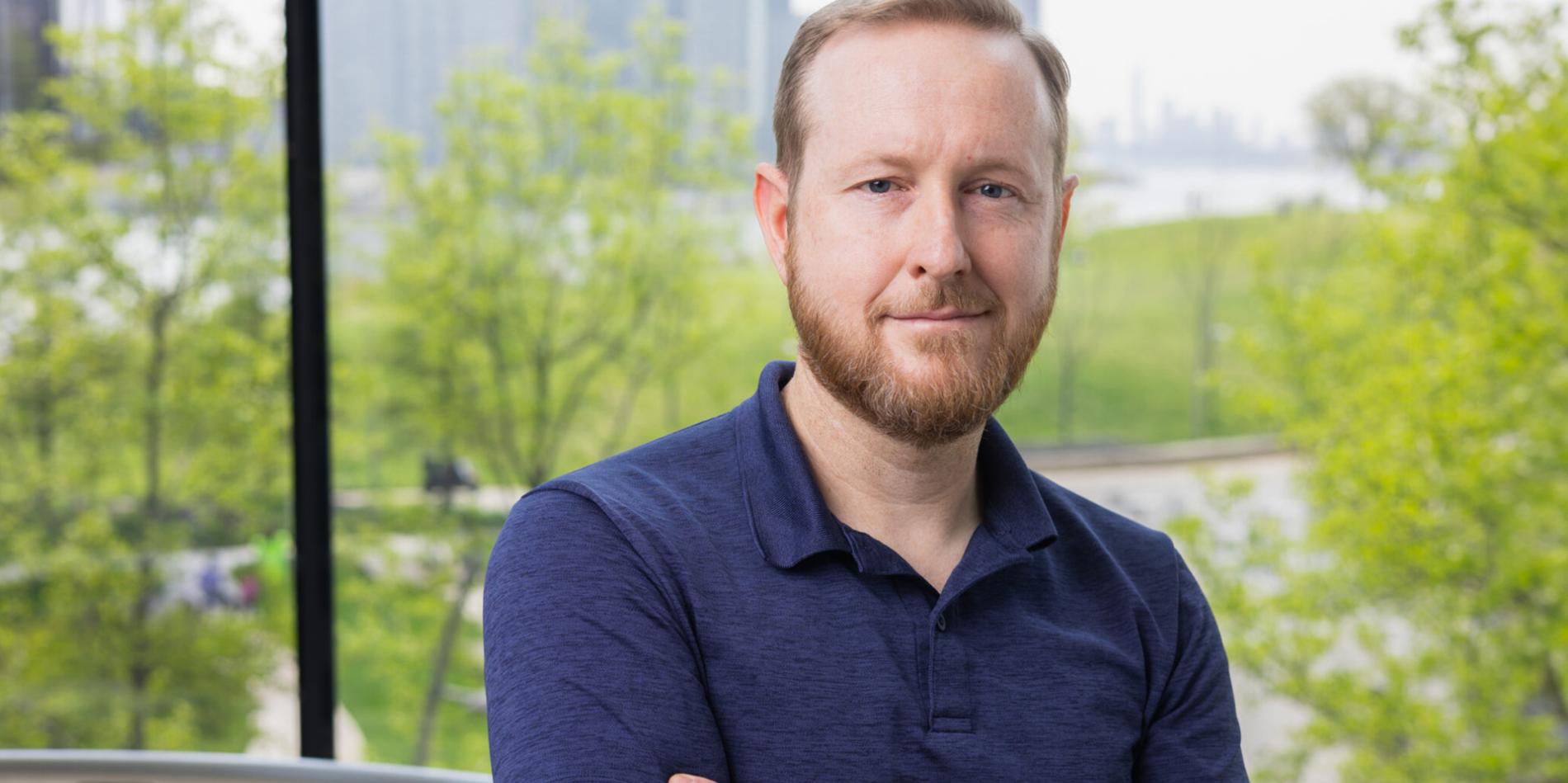 A color photo of a man smiling for a portrait.