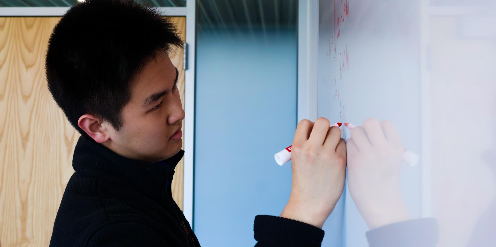 Andrew Kang writes on a white board