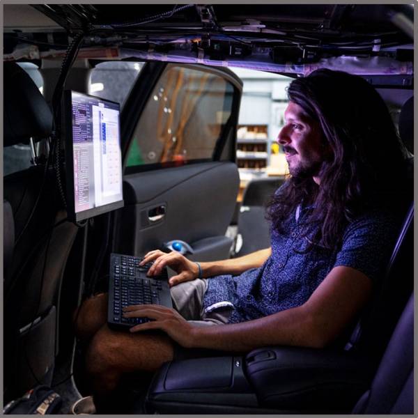 man working on computer in back seat of autonomous vehicle