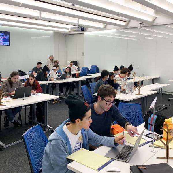 A color photo showing a room full of students working on computer programming