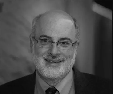 A black and white photo of Kenneth Birman, a man with glasses wearing a suit and tie.