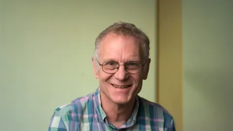 A photo of Dexter Kozen, a smiling man with short gray hair, glasses and a plaid shirt