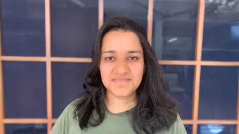 A photo of Tanya Goyal, a woman with shoulder-length dark brown hair in a green shirt.