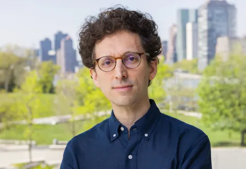 A color photo of Yoav Artzi infront of a city park background