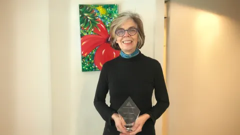 A color photo of a woman holding a glass award.