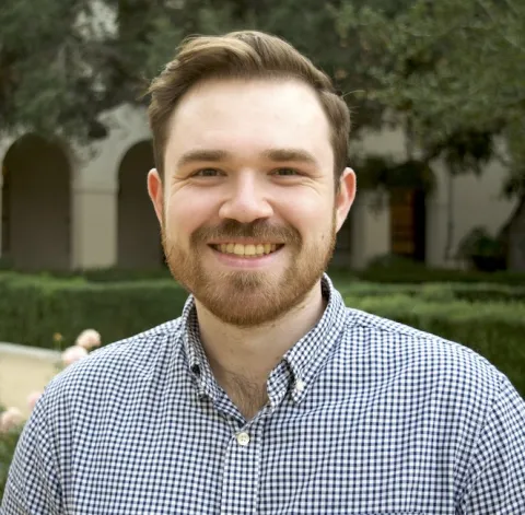 Color portrait Preston Culbertson smiling at the camera; short brown hair wearing checker shirt