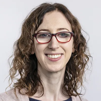 Women with glasses, curly hair, smiling at camera