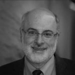 A black and white photo of Kenneth Birman, a man with glasses wearing a suit and tie.