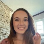 A color photo of a woman smiling for a photo.