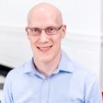 a bald man with glasses wearing a light blue button down shirt