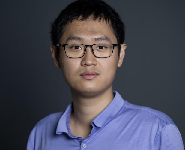 A color photo of a man with glasses.