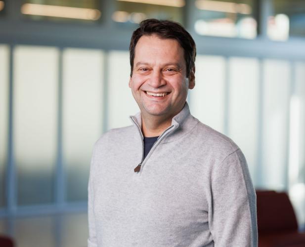 a man with short brown hair wearing a gray sweater