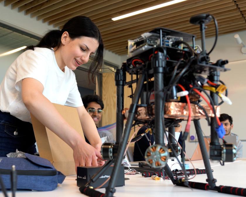 A color photo of a woman working on a drone.