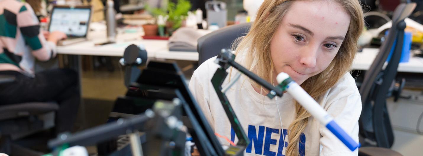 A color photo of a woman working on a robotics project.