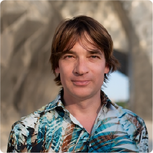 A color photo of a man standing outside.