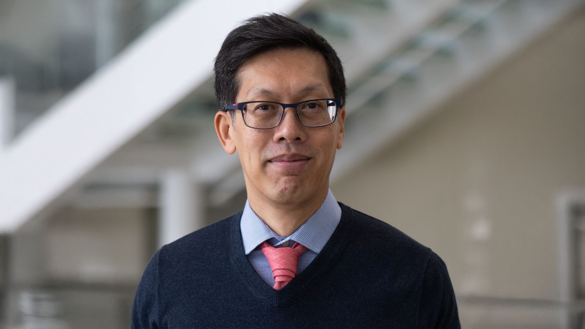 A color photo of Rich Vuduc standing outside wearing a dress shirt, tie, and v-neck sweater.