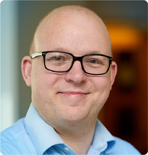 A color photo of a man with glasses.