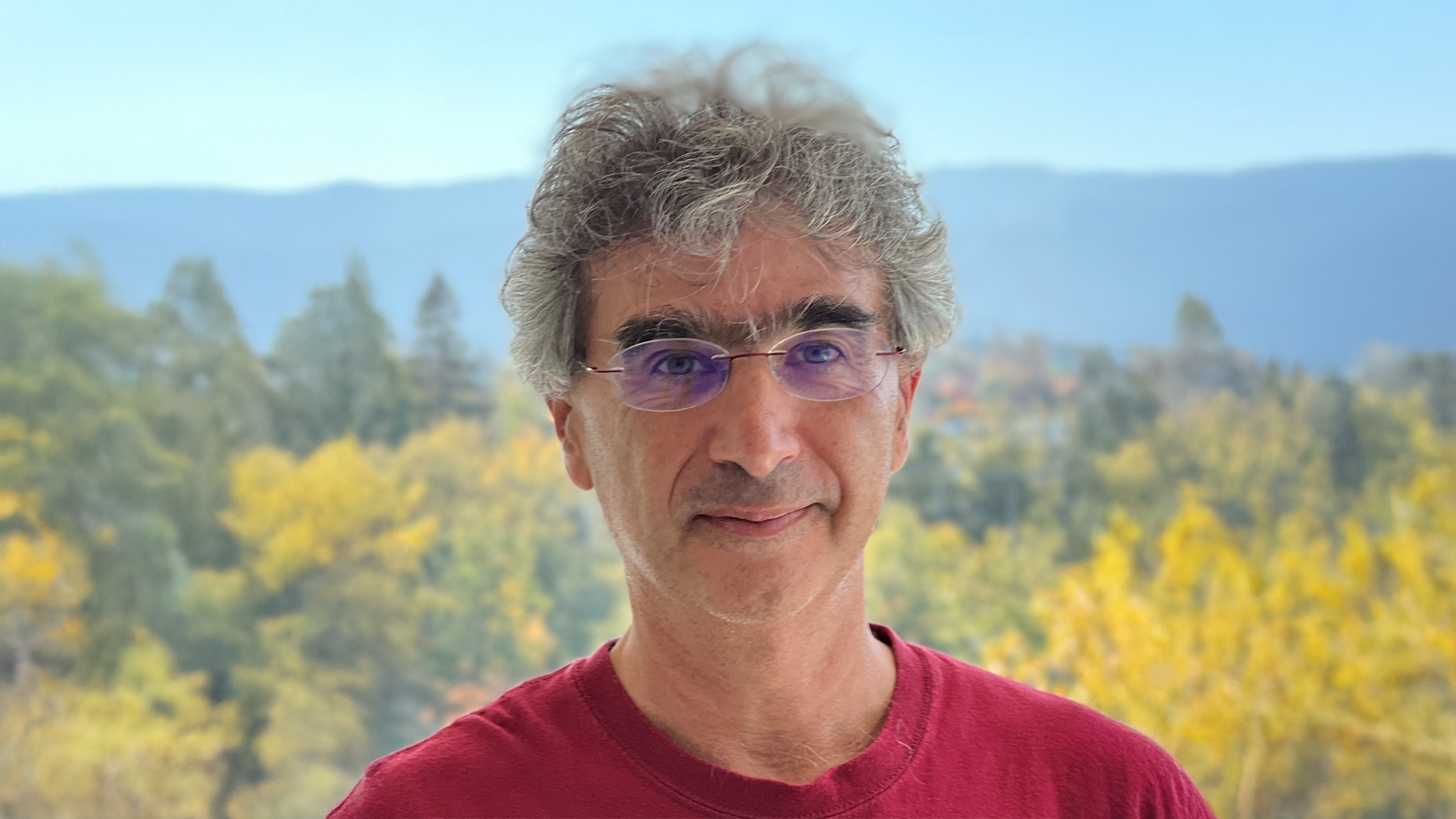 A color photo of a man standing outdoors.