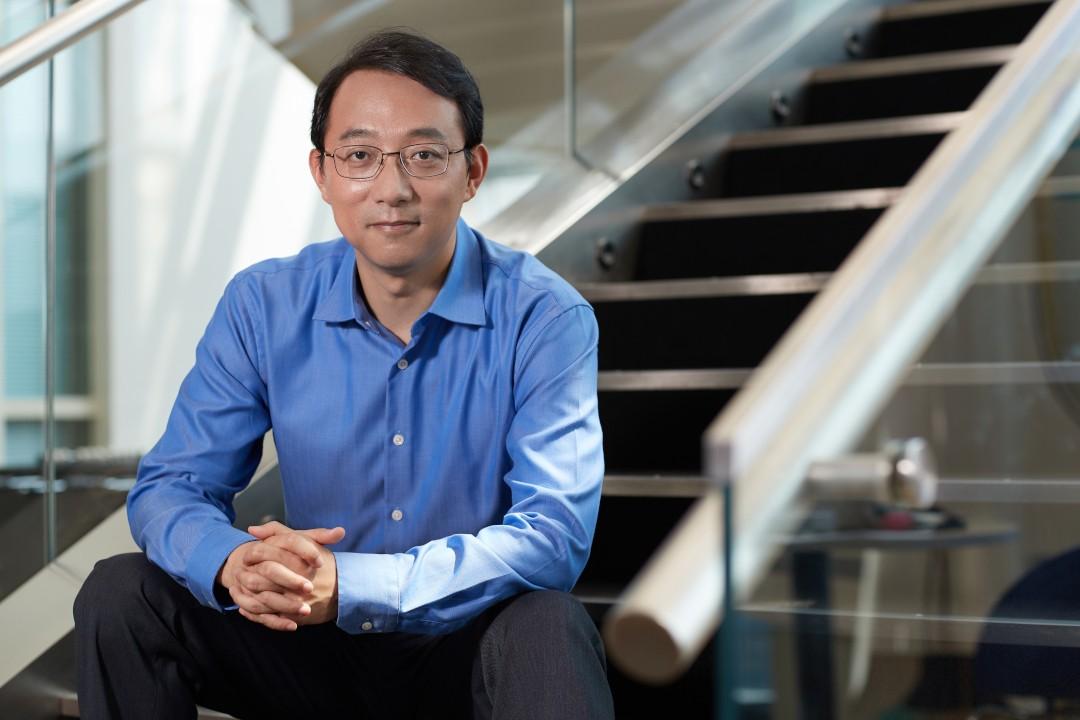 A color photo of a man sitting on a staircase.