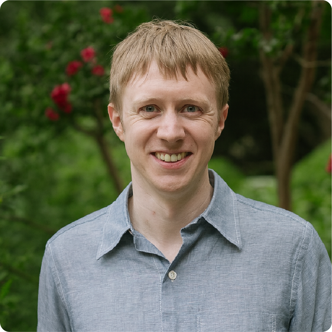 A color photo of a man standing outside.