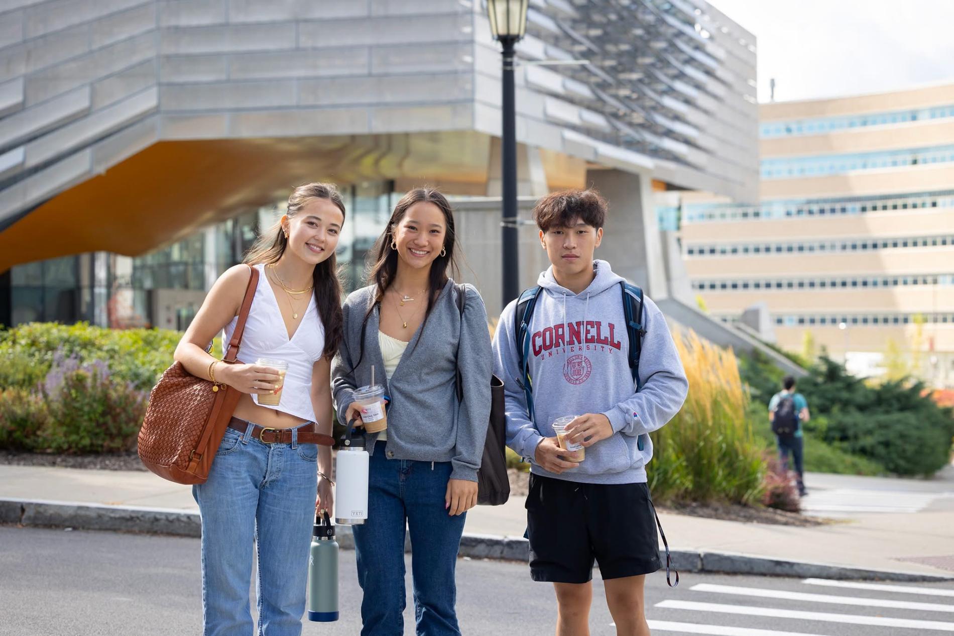 three students stand in front of Gates hall