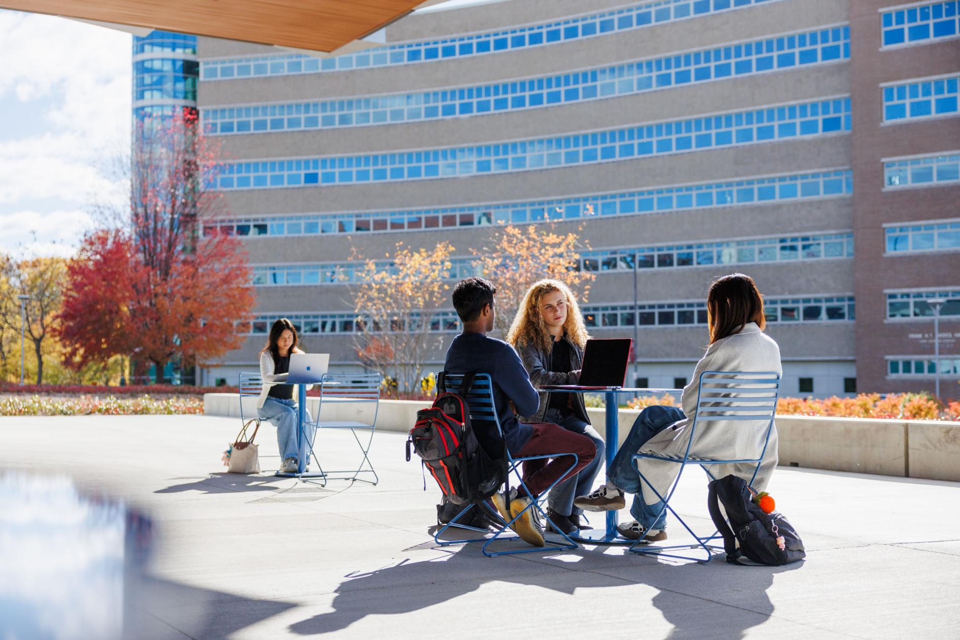 a group of students sit around a table outside